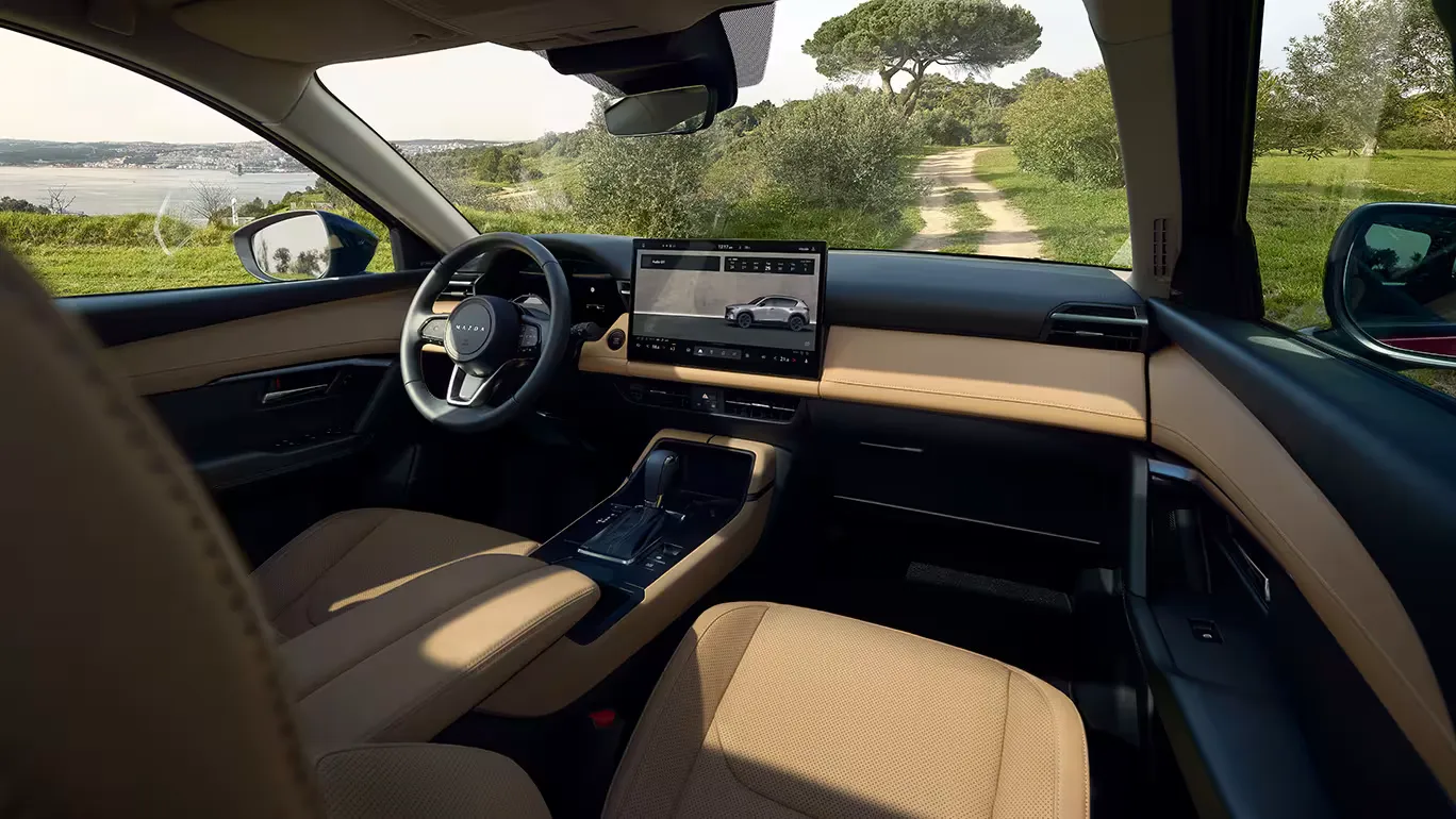 Mazda CX-5 belső tér modern műszerfallal, központi kijelzővel és ülésekkel, kilátással egy vidéki útra